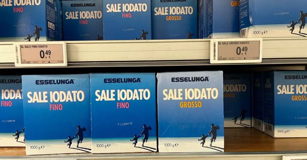The image shows a series of cardboard packages filled with coarse iodized salt (the typical salt used for salting pasta during cooking), available on the shelves of all Italian supermarkets.