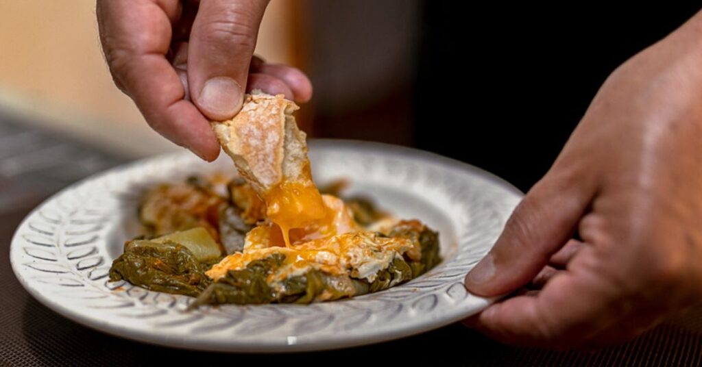 Someone dipping bread in acquacotta soup bowl