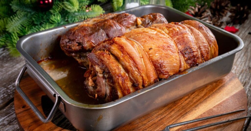 A baking tray with two baked stuffed rabbits wrapped in slices of crispy pancetta (a type of bacon).