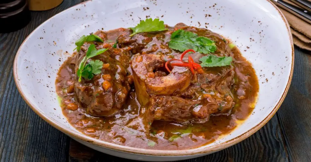 A plate of veal shanks braised in a flavorful sauce made from tomatoes, onions, carrots, celery.