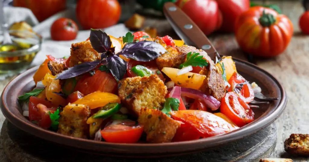 On the plate is a Tuscan panzanella salad, made with soaked stale bread and fresh vegetables, all seasoned with olive oil, a fresh and traditional dish.