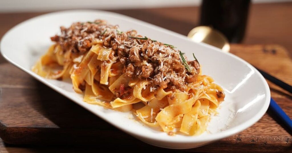 A plate of long pasta topped with a ragout of geese.