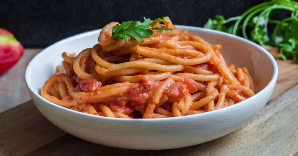 Plate of Pici all'Aglione Toscani freshly served, like very thick spaghetti seasoned with tomato sauce and garlic.