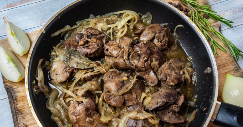 A pan full of marinated pieces of pork liver seasoned with pepper and bay leaves.