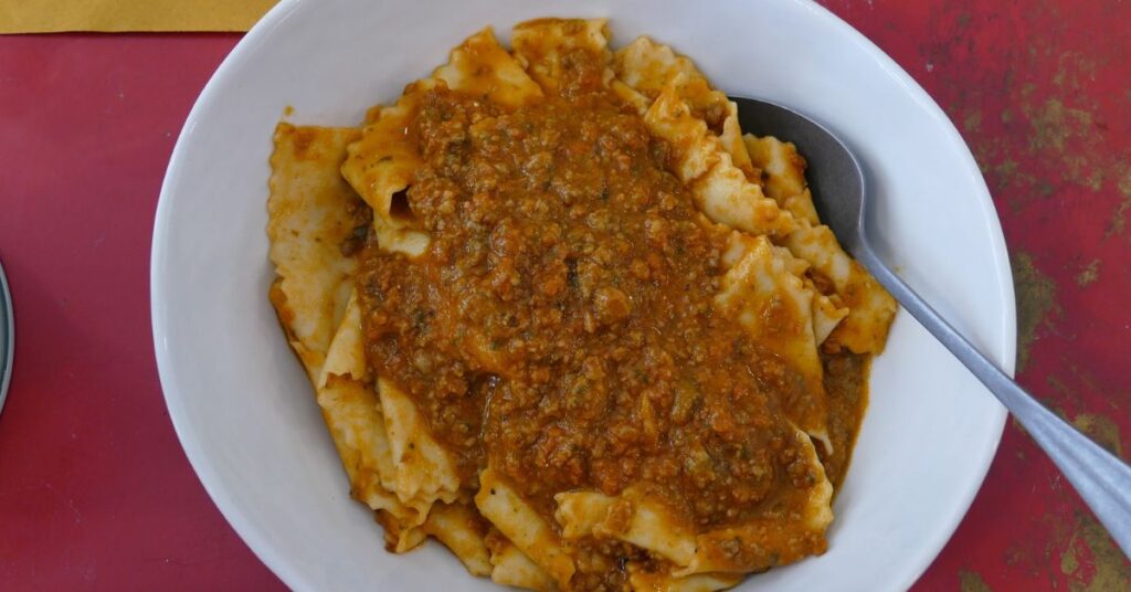 A plate of steaming Tordelli pasta with ragout meat sauce.