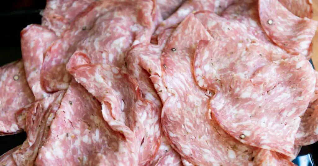 Finely cut slices of Finocchiona salami, a very fresh salami with a light pink color dotted with white fat.
