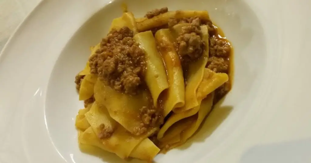 A dish containing Maccheroni di San Jacopo, seasoned with a bordeaux-red duck ragout with the grainy appearance of the minced meat.