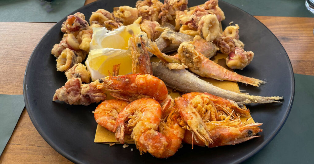 A plate of different fried fish and creostaceans, they are golden and crispy.