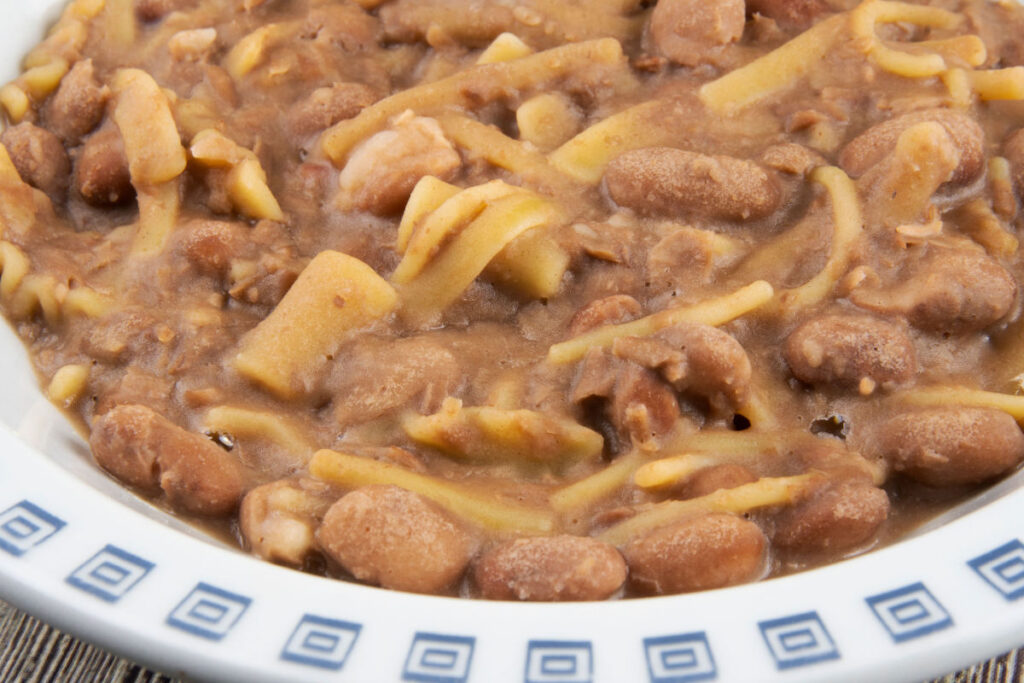 A pasta dish where the pasta literally drowns in a thick brown colored cream, which is made from mashed beans sautéed in a pan.