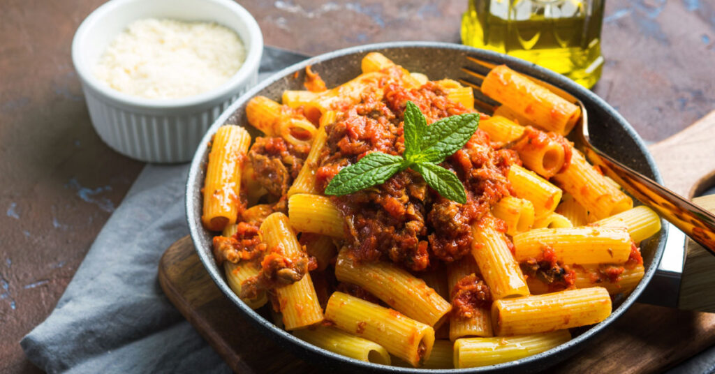 A plate of rigatoni pasta topped with a tomato and meat sauce, also known as Red Ragù.