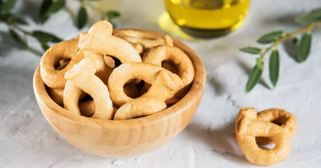 A small bowl full of small savory taralli, crunchy in appearance and with an amber colour.