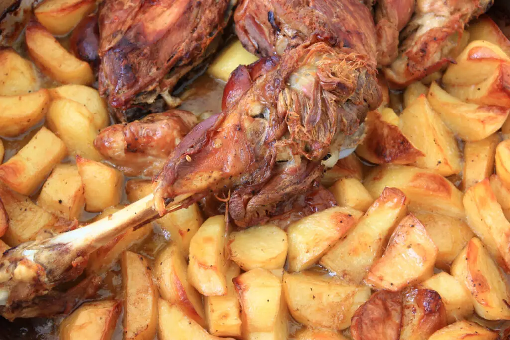 Legs of lamb cooked in the oven on a bed of crispy potatoes.