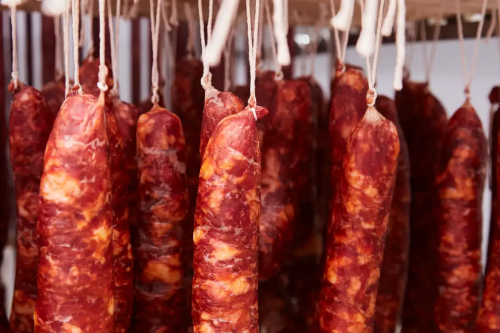Some spicy salamis hung to mature are brown/red in color and have a rustic and irregular appearance.