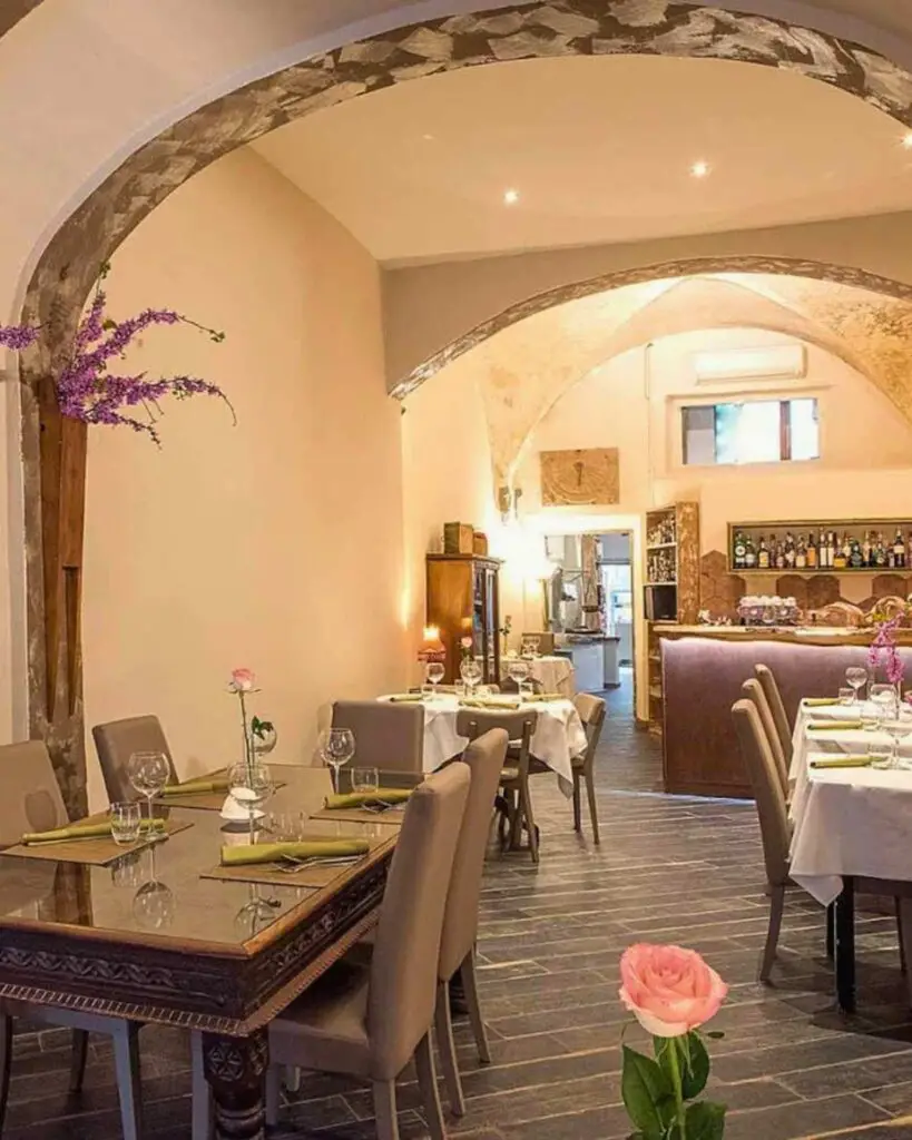 Elegant dining area inside Cuculia, one of the best restaurants in Florence, with historical stone arches and chic decor.