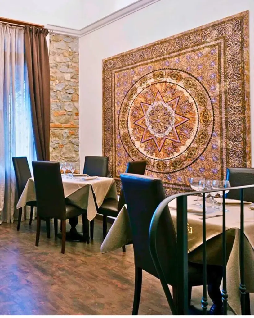 Interior view of L'Insolita Trattoria Tre Soldi, showcasing a cozy dining room with stone walls and elegant decor, creating an intimate atmosphere in Florence.