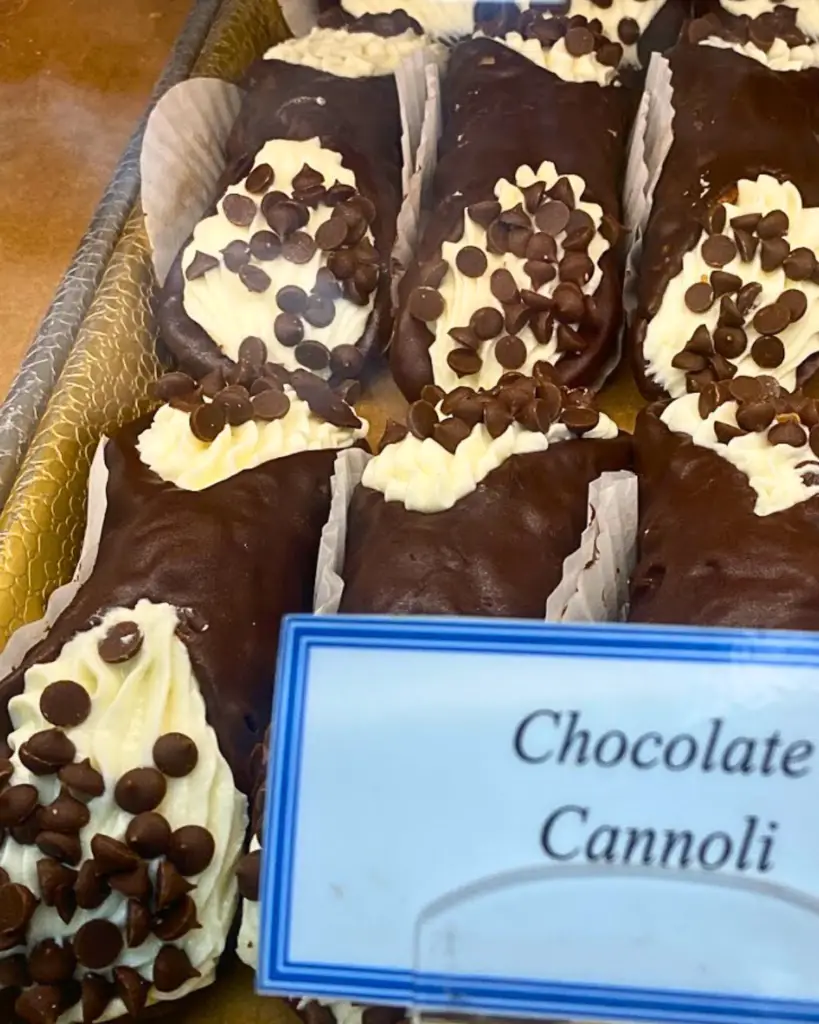 A tray of chocolate-covered cannoli with ricotta filling and chocolate chips at Gian Piero Bakery in NYC.