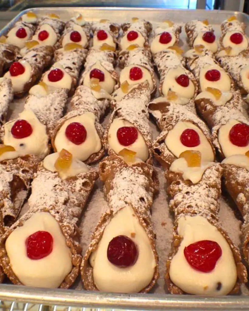 Best cannoli in NYC at Villabate Alba, beautifully displayed with cherries and powdered sugar.