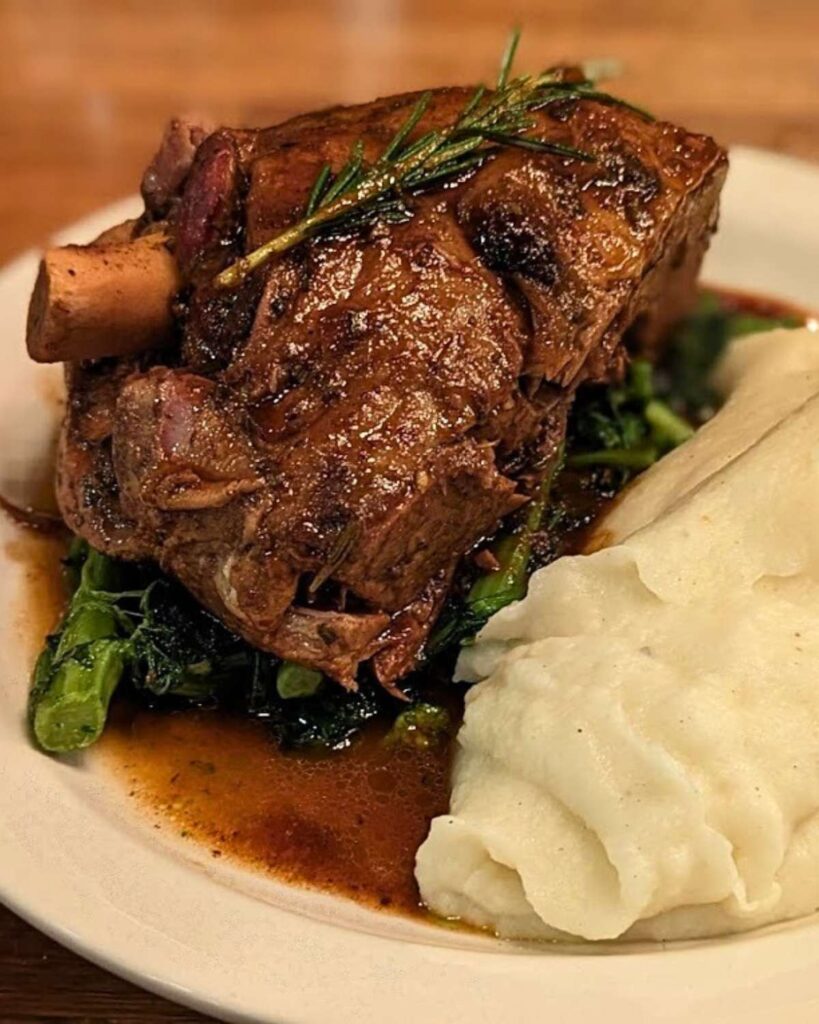 A succulent lamb shank with creamy mashed potatoes served at Camillo in Brooklyn, a top-rated Italian restaurant in NYC.