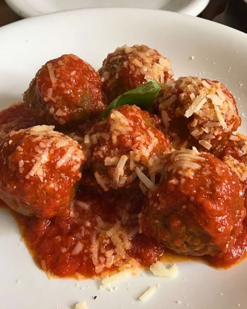 A plate of flavorful meatballs topped with rich tomato sauce and grated Parmesan cheese, served at Lillo Cucina Italiana, one of the best Italian restaurants in New York.