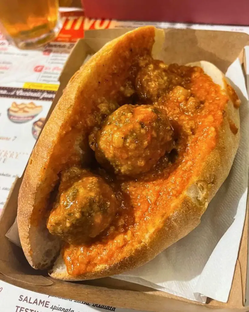 A close-up of a traditional ciriola sandwich filled with meatballs in tomato sauce, a classic local food in Rome from Dar Ciriola.