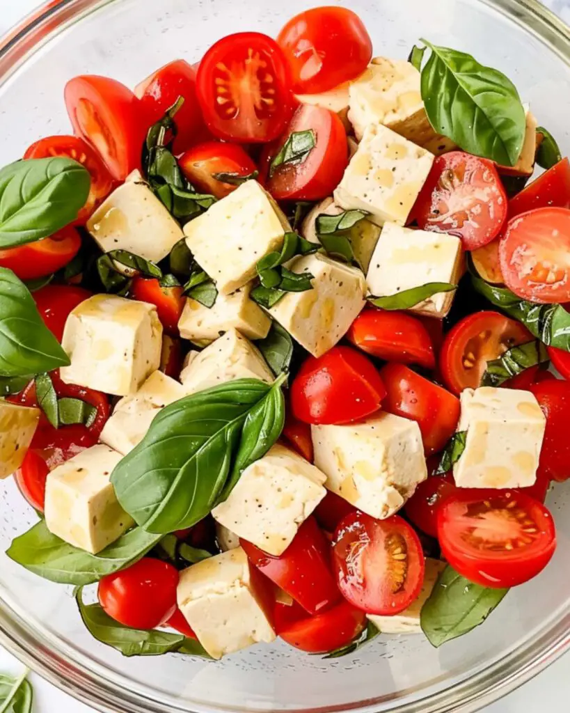 Vibrant gluten free Caprese salad with cherry tomatoes, fresh mozzarella, and basil, drizzled with balsamic dressing.