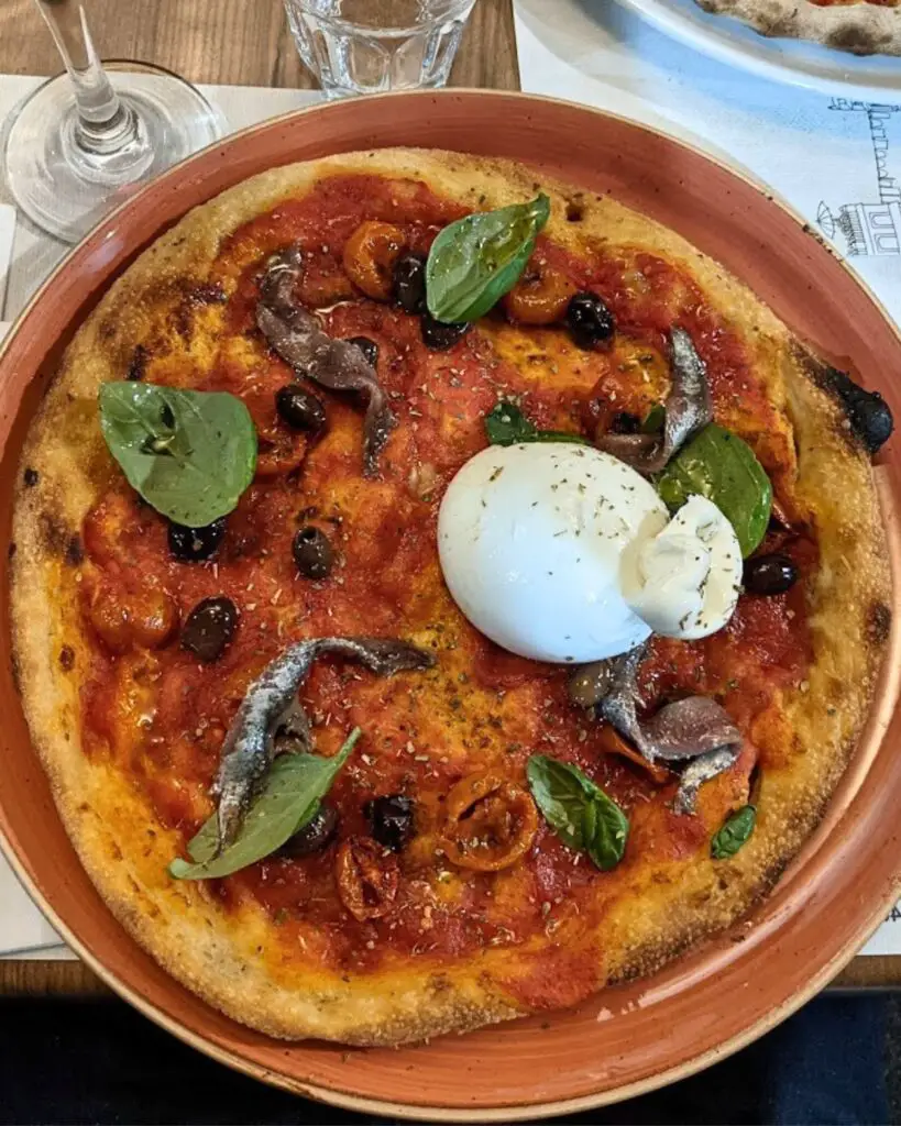 A delicious pizza featuring a perfectly balanced crust and fresh toppings at Al Grottino in Rome, where culinary traditions meet craft beer.