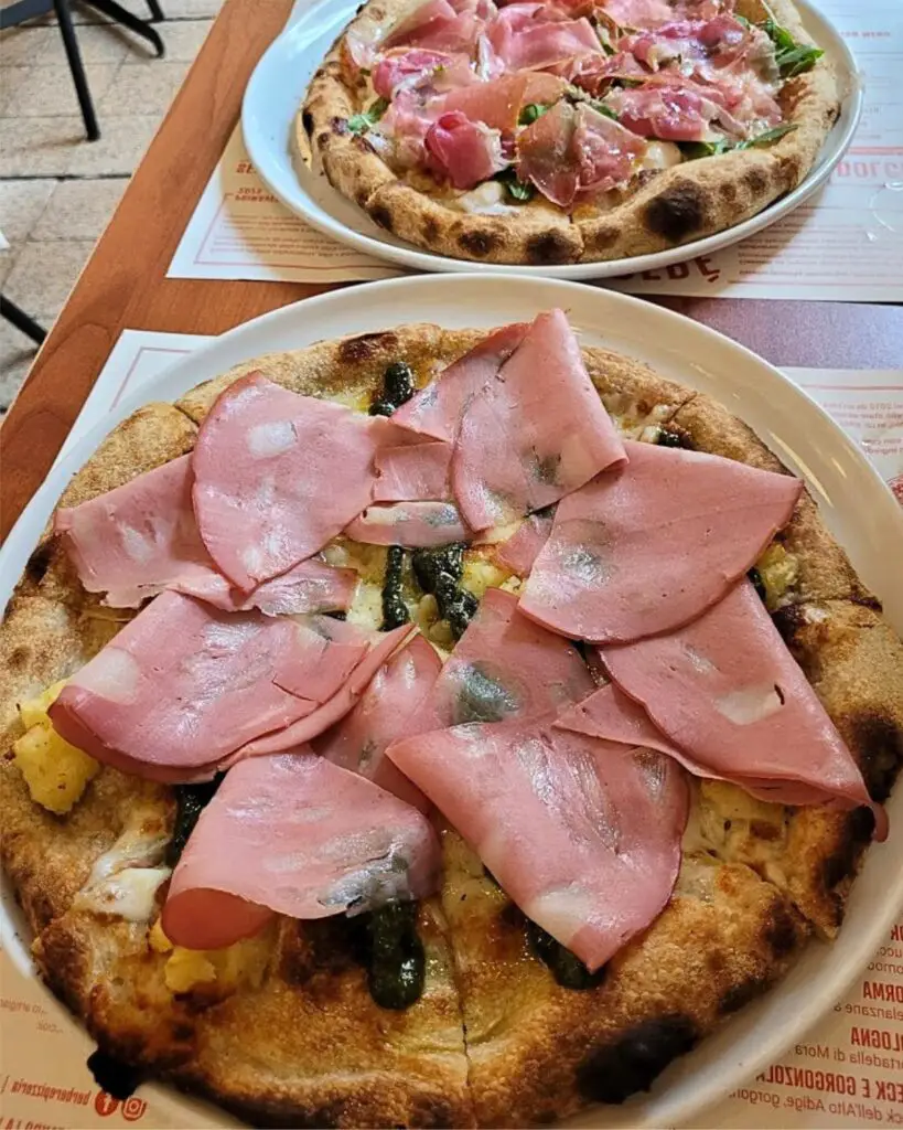 A mouthwatering pizza topped with prosciutto and unique ingredients at Berberè, showcasing exceptional Rome pizza quality.