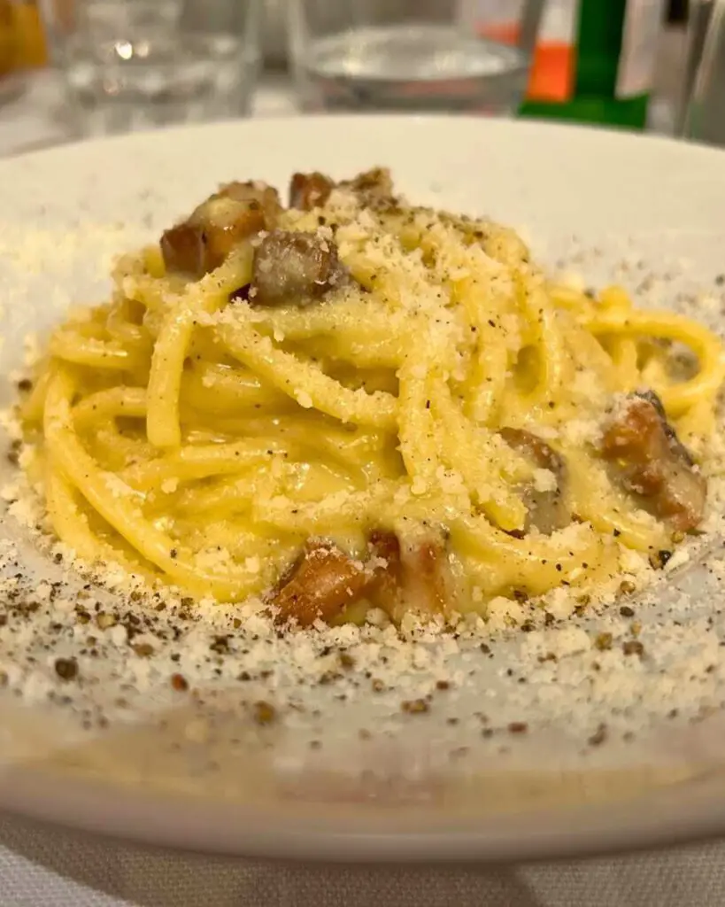 A close-up of spaghetti carbonara Rome at Roscioli Salumeria con Cucina, featuring perfectly cooked spaghetti with creamy sauce, crispy guanciale, and a generous sprinkling of Pecorino Romano, showcasing the carbonara Rome aesthetic.