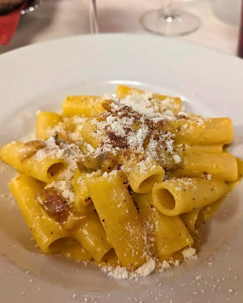 A plate of authentic pasta carbonara at Trattoria Sora Lella in Rome, featuring perfectly cooked rigatoni, creamy sauce, and sprinkled Pecorino Romano, showcasing the Rome pasta dishes.