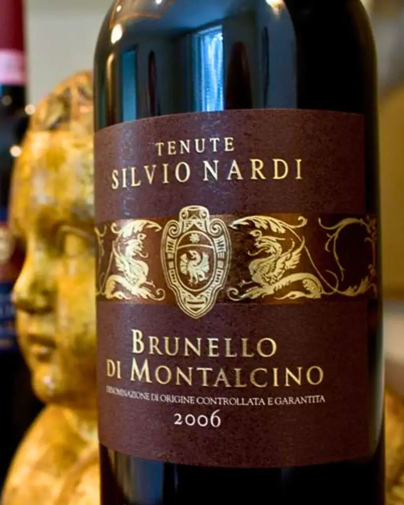 Bottle of Brunello di Montalcino, one of the best Italian wines, known for its rich flavor and aging potential, standing next to another Italian wine bottle with an antique background.