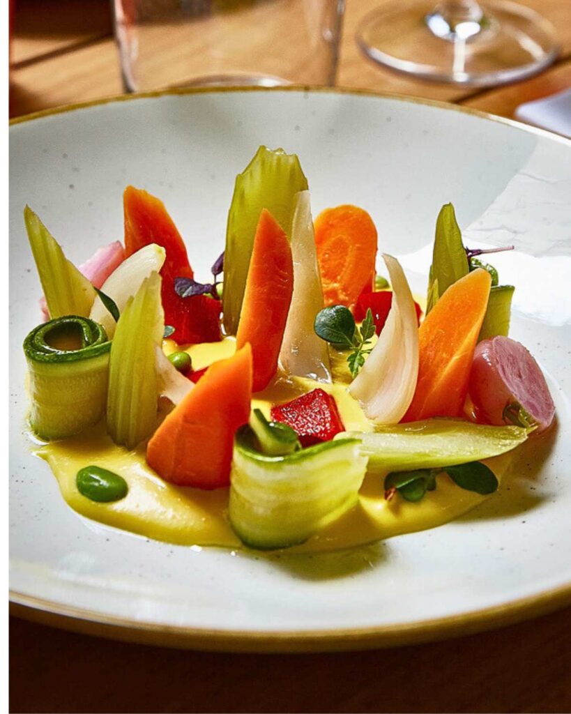 Beautifully plated vegetables including carrots, radishes, celery, and microgreens on a bed of creamy sauce at Aromaticus, one of the best vegan restaurants in Rome, known for its creative vegan dishes and fresh ingredients.