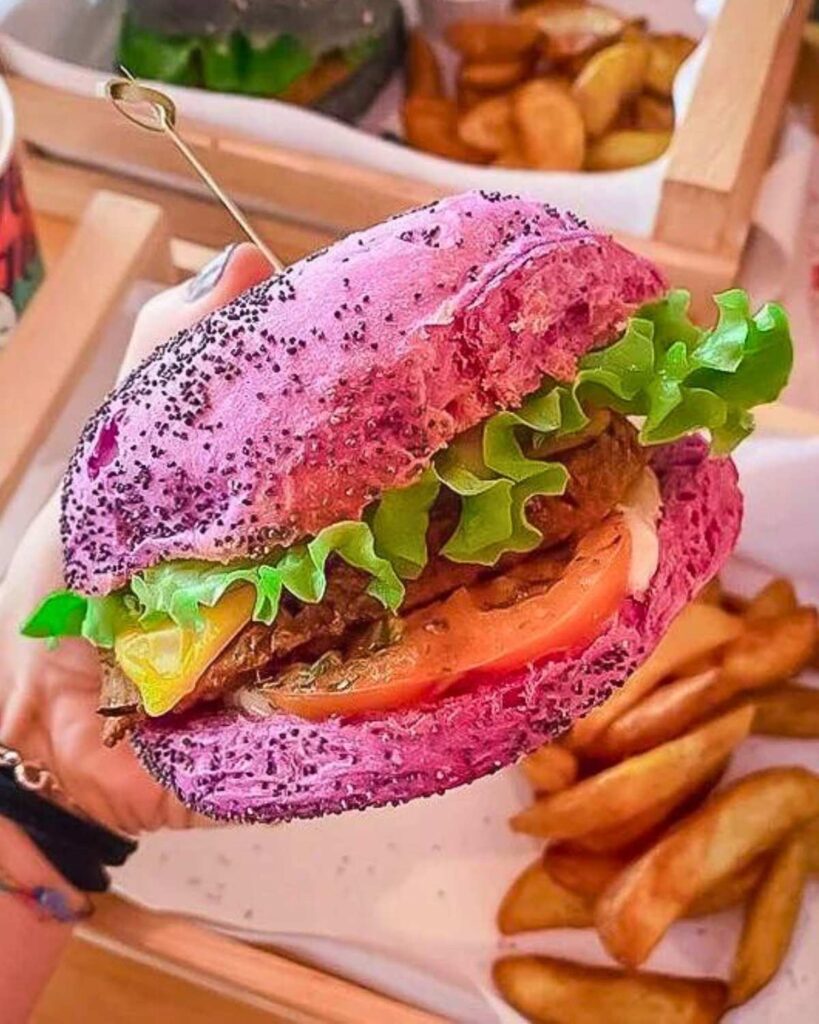 Brightly colored vegan burger with a pink bun, lettuce, tomato, and vegan patty at Flower Burger, a popular vegan restaurant in Rome.