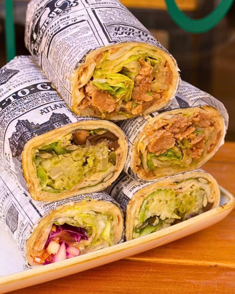 A variety of vegan wraps filled with fresh vegetables, wrapped in newspaper-style paper, served at Il Borgo Verde Salad & Juice Bar, a top spot for vegan food in Rome.