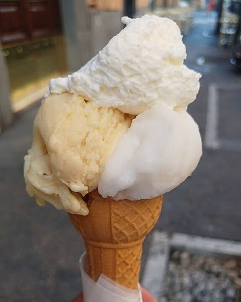 A cone with three scoops of gelato from Gelateria dei Gracchi in Rome, featuring a mix of flavors and a creamy texture, showcasing the best ice cream in Rome with an authentic gelato Rome aesthetic.