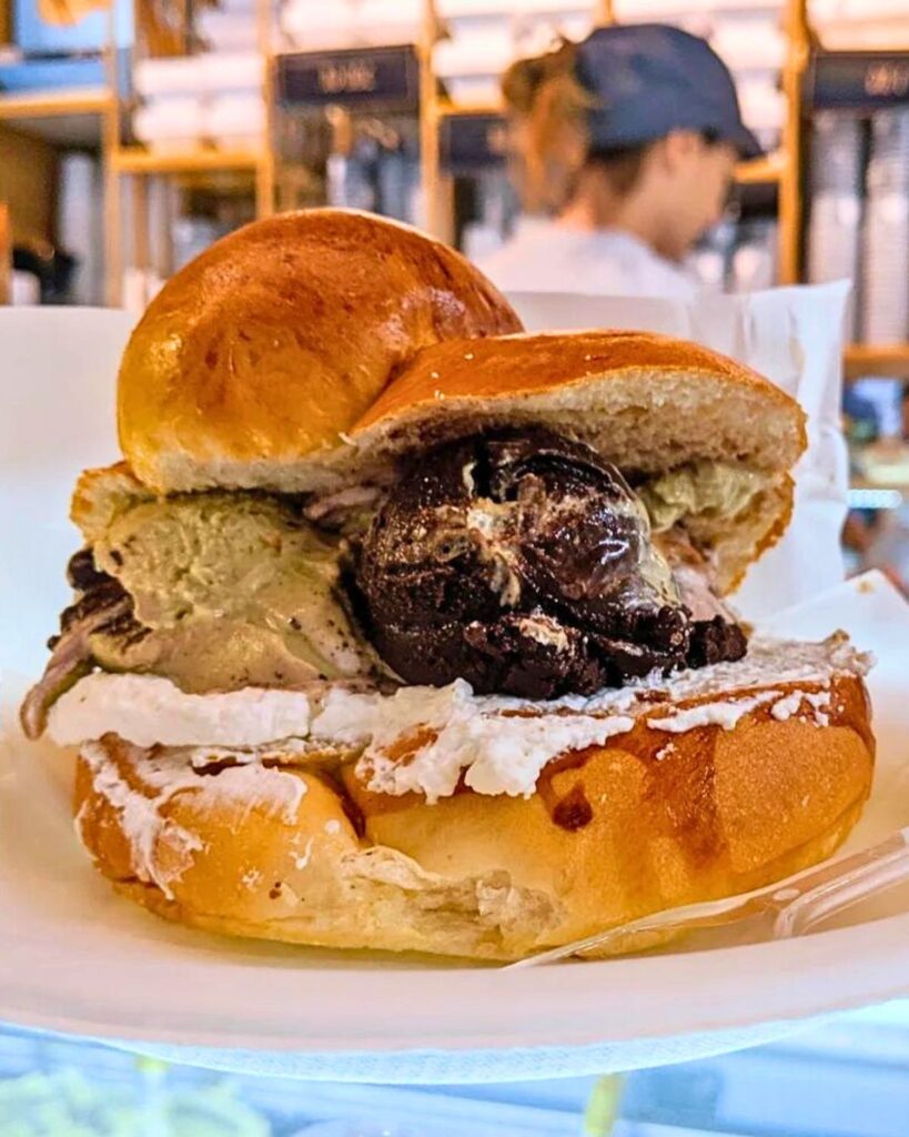 A gelato sandwich from Neve di Latte in Rome, featuring scoops of rich gelato inside a brioche bun, showcasing the best ice cream in Rome Italy with a unique and authentic gelato Rome aesthetic.