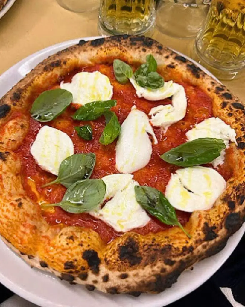 Fresh mozzarella and basil topping a vibrant tomato base on a pizza at La Gatta Mangiona, highlighting why it's one of the best pizza places in Rome.