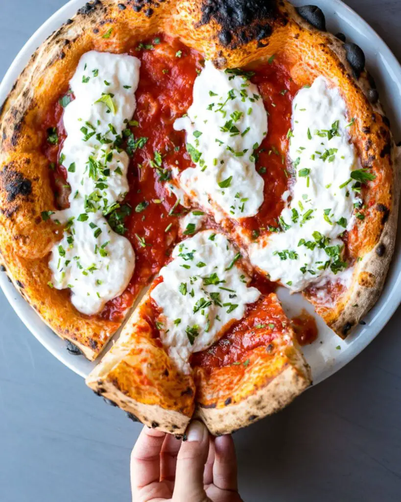 Hand pulling a slice from a Neapolitan-style pizza at Sbanco, featuring creamy mozzarella and fresh basil—a staple for the best pizza in Rome.