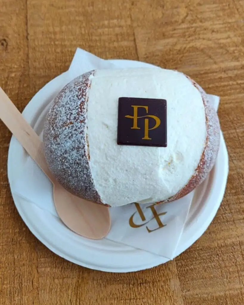 Famous maritozzo from Federico Prodon Pâtisserie in Rome, topped with fresh whipped cream and a chocolate logo.