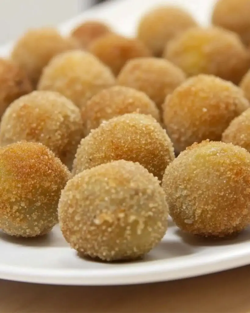 Close-up of crispy golden Italian Fried Stuffed Olives, known as Olive all’ Ascolana, served on a white plate. These savory appetizers are filled with a rich meat stuffing and are perfect for adding an authentic touch to an Italian-themed Thanksgiving dinner.