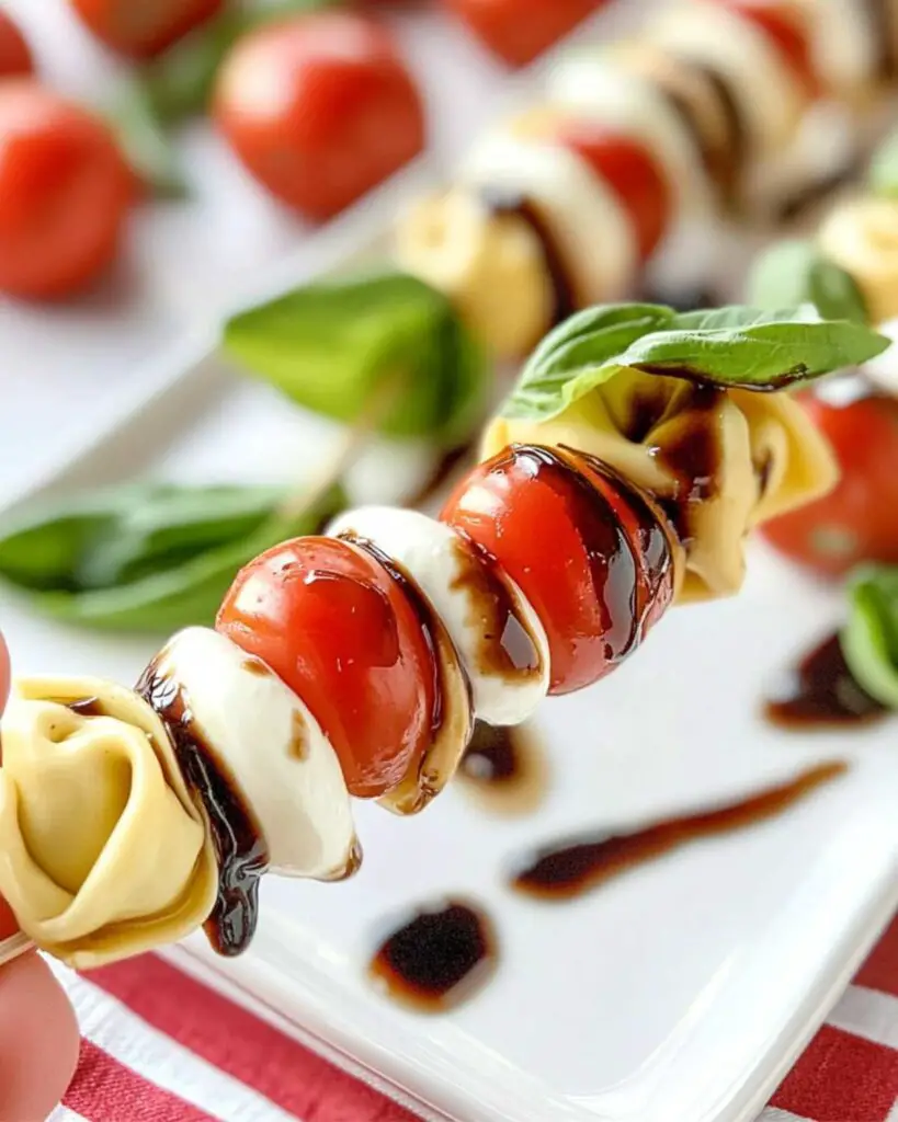 Tortellini Caprese skewers featuring Italian Thanksgiving ingredients like fresh mozzarella balls, cherry tomatoes, basil leaves, and tortellini pasta, all drizzled with a balsamic glaze, perfect for a traditional Italian Thanksgiving appetizer.