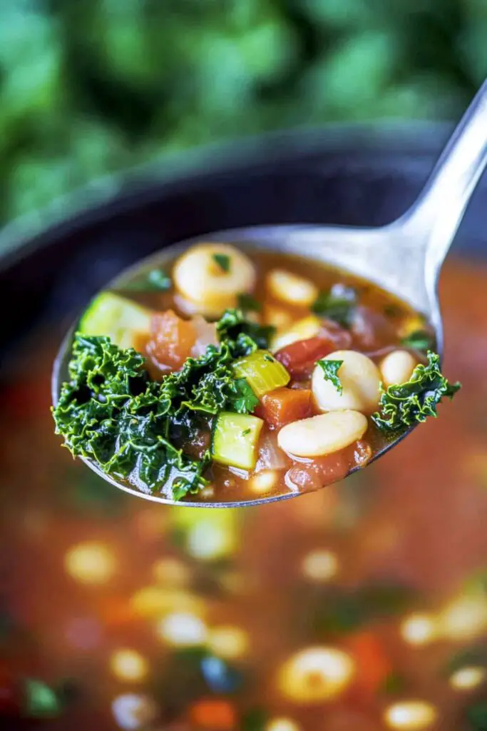 A ladle of Italian vegetable soup with kale, shell pasta, and beans in a rich vegetable broth, served hot and fresh.