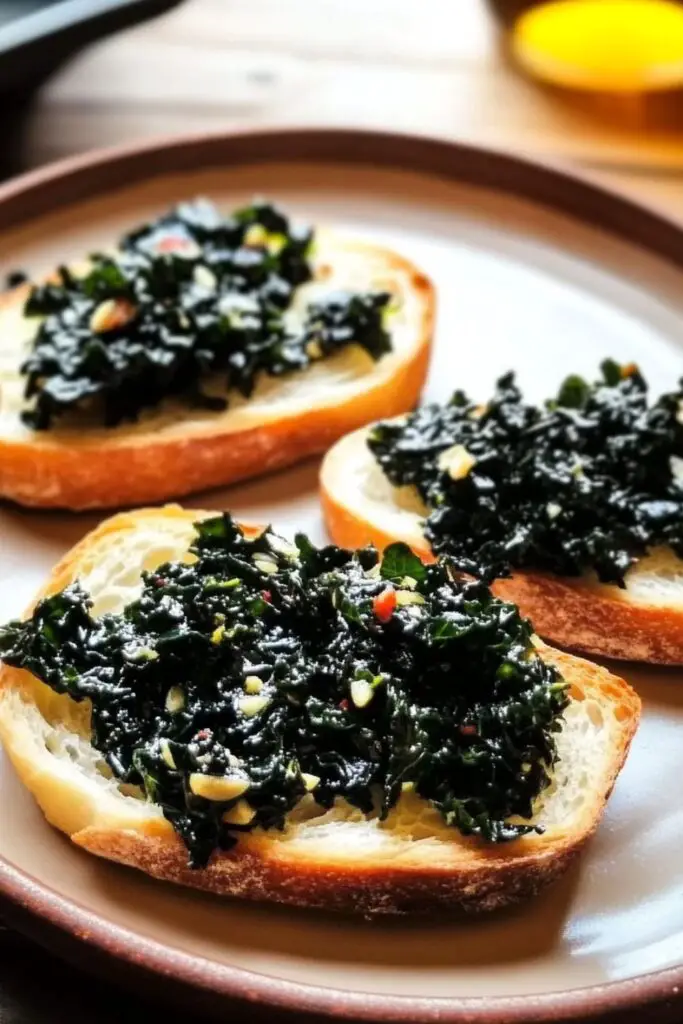 Slices of rustic Tuscan bread topped with sautéed black kale (cavolo nero) drizzled with olive oil, served as a classic bruschetta appetizer.