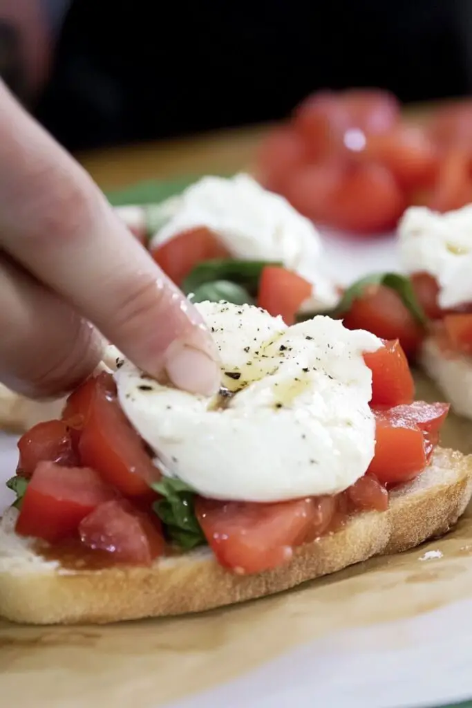 Hand preparing bruschetta with fresh tomatoes and mozzarella on toasted bread