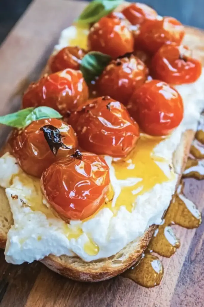 Crispy toasted bread topped with creamy burrata cheese, juicy roasted cherry tomatoes, and a drizzle of honey, creating a rich, flavorful Italian bruschetta appetizer perfect for any gathering