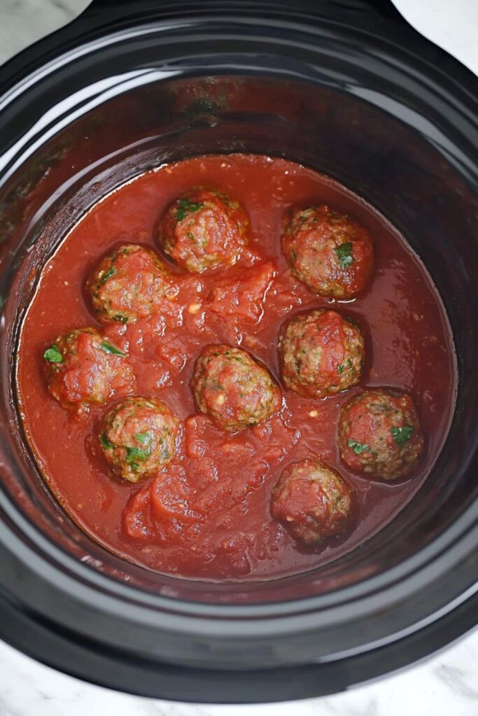 A slow cooker filled with homemade Italian meatballs simmering in rich tomato sauce, perfect for a crockpot meal.