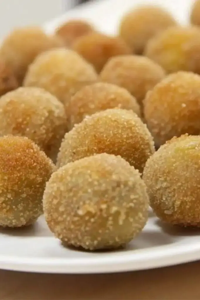 Close-up of crispy golden Italian Fried Stuffed Olives, known as Olive all’ Ascolana, served on a white plate. These savory appetizers are filled with a rich meat stuffing and are perfect for adding an authentic touch to an Italian-themed Christmas dinner.