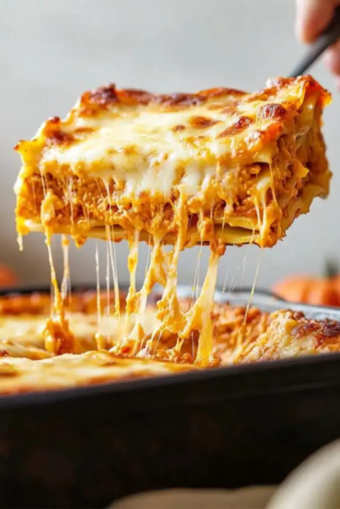 A serving of pumpkin lasagna being lifted from a baking dish, perfect for an Italian-themed Christmas celebration.