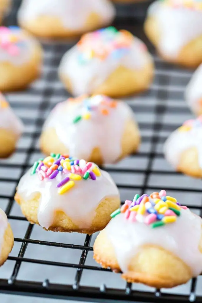 Close-up of freshly baked Italian knot cookies with a smooth lemon glaze and colorful sprinkles, perfect for festive occasions. These classic Italian Christmas biscuits are soft and fluffy, ideal for those searching for easy Italian Christmas cookie recipes.