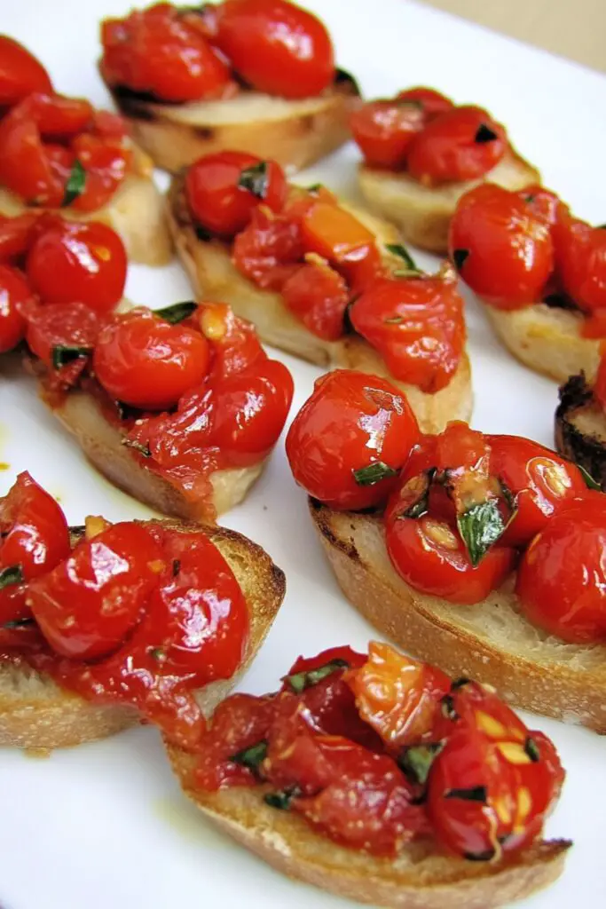 Roasted cherry tomatoes served on crispy baguette slices, drizzled with olive oil and seasoned with garlic, oregano, and basil for a classic Italian bruschetta appetizer