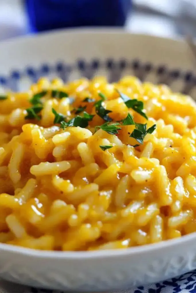 Traditional Italian Christmas pasta risotto made with pumpkin, creamy and comforting, garnished with fresh parsley in a white bowl.